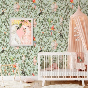 May include: A nursery scene featuring a white crib, a pink canopy, and a framed print of two cockatoos. The wallpaper has a repeating pattern of birds and foliage in shades of green, pink, and red. A wooden play gym and a fluffy rug complete the room.
