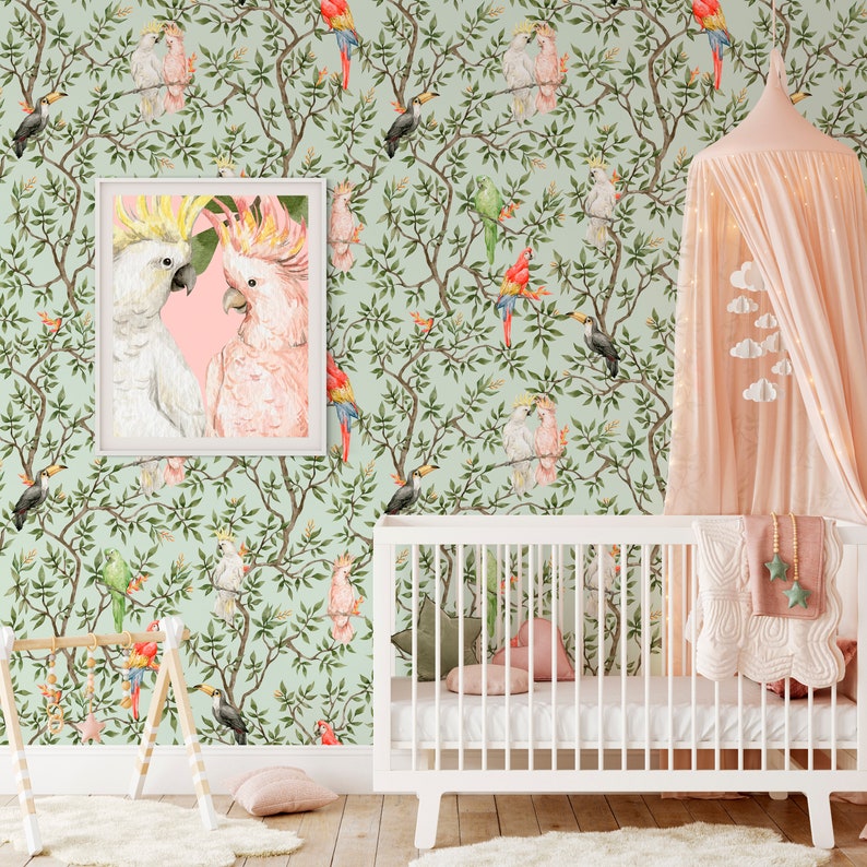 May include: A nursery scene featuring a white crib, a pink canopy, and a framed print of two cockatoos. The wallpaper has a repeating pattern of birds and foliage in shades of green, pink, and red. A wooden play gym and a fluffy rug complete the room.