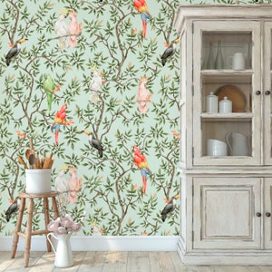 May include: Watercolor wallpaper featuring a repeating pattern of colorful parrots, toucans, and cockatoos perched on leafy branches against a light green background. The design includes a wooden cabinet, a stool, and a white pitcher.