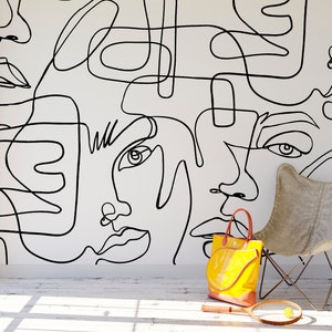 Minimalist continuous line art wallpaper with overlapping abstract faces in black on a light backdrop. Ideal for Scandinavian inspired decor, neutral living spaces, creative studios and apartment accent walls in modern homes.