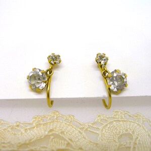 May include: A pair of gold-tone clip-on earrings with clear rhinestone accents.