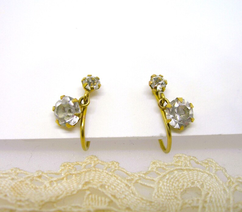 May include: A pair of gold-tone clip-on earrings with clear rhinestone accents.