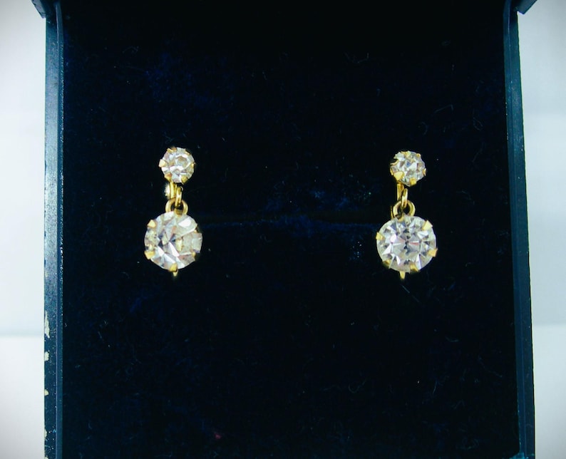 May include: A pair of gold earrings with two clear round stones on each earring.