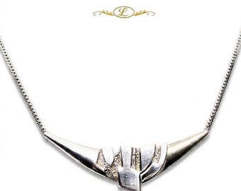 Puede incluir: Un collar de tono plateado con un colgante curvo en forma de media luna con un diseño metálico texturizado de varias capas. El colgante está unido a una cadena fina y flexible de tono plateado. Un pequeño logotipo con la letra L es visible arriba.