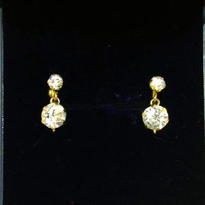 May include: A pair of gold earrings with a single round clear stone on each earring.