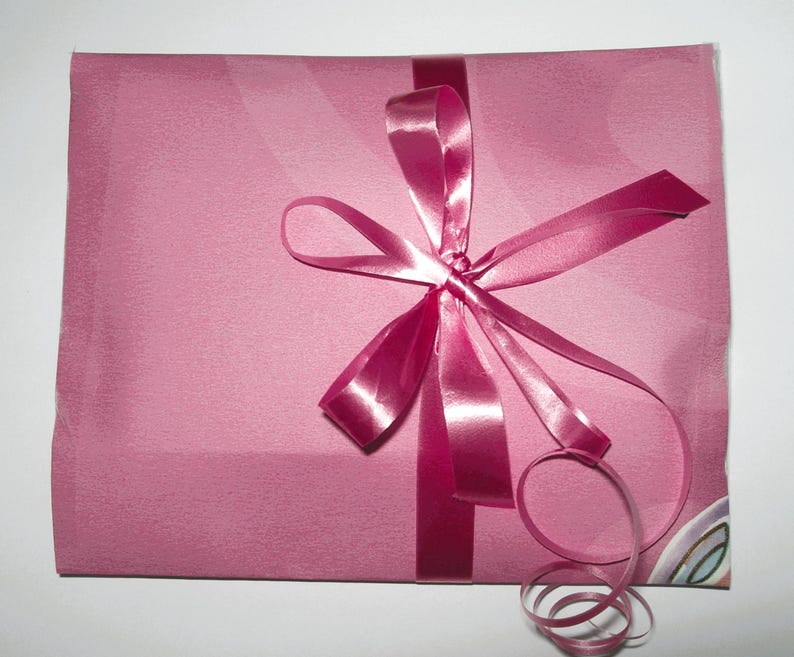 May include: A pink gift bag with a pink satin ribbon tied in a bow. The ribbon has a long tail that is curled.