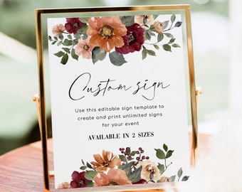 May include: A rectangular gold metal frame holding a white sign with watercolor floral illustrations in shades of burgundy, orange, and green. The text reads: Custom sign, Use this editable sign template to create and print unlimited signs for your event, AVAILABLE IN 2 SIZES.