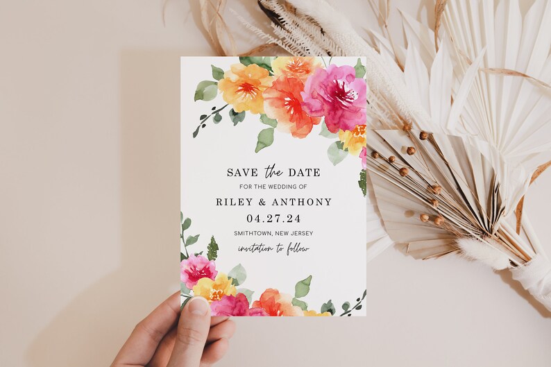 May include: Save the date card with watercolor floral design in shades of pink, orange, and yellow. The text reads "Save the Date for the wedding of Riley & Anthony 04.27.24 Smithtown, New Jersey invitation to follow."