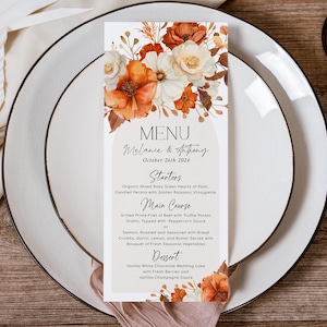 Könnte beinhalten: Eine rechteckige Hochzeitsmenükarte mit einem Aquarell-Blumenarrangement in Orange-, Rost- und Cremetönen oben und unten. Der Text lautet MENU, Melanie & Anthony, October 26th 2024, Starters, Main Course und Dessert mit den jeweiligen Speisen.