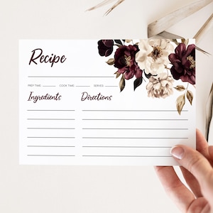 Può includere: Biglietto di ricetta con design floreale. La carta presenta la parola "Recipe" in un carattere script bordeaux. L'angolo in alto a destra è adornato da fiori bordeaux, crema e oro. La carta include sezioni per il tempo di preparazione, il tempo di cottura, le porzioni, gli ingredienti e le istruzioni.
