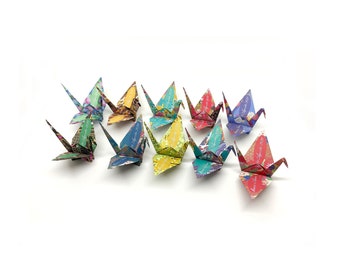 Może przedstawiać: Kolekcja 10 kolorowych żurawi origami wykonanych z wzorzystego papieru. Żurawie są ułożone w rzędzie, z głowami skierowanymi w prawo.