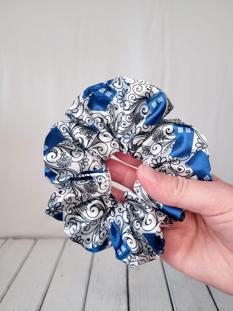 Pu&ograve; includere: Un elastico per capelli bianco e blu con un design blu TARDIS. L'elastico &egrave; fatto di tessuto satinato e ha una texture arricciata.
