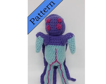 May include: A crocheted plush toy in the shape of a creature with a purple body, blue legs, and pink eyes. The toy has a long tail and four legs.