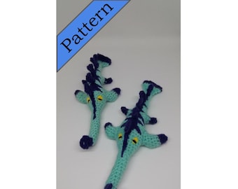 May include: Two crocheted seahorse toys, one larger than the other, are both teal blue with dark blue stripes and yellow eyes. The toys are posed on a white background.