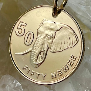 Puede incluir: Una moneda de color dorado con la cabeza de un elefante y el texto "50 FIFTY NGWEE".