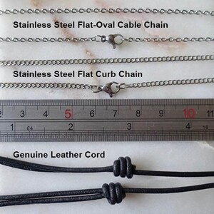 Puede incluir: Primer plano de tres estilos de cadenas de collar: cadena plana ovalada de acero inoxidable, cadena plana de eslabones de acero inoxidable y cord&oacute;n de cuero genuino. Una regla muestra las medidas en cent&iacute;metros. Texto que etiqueta cada tipo de cadena.