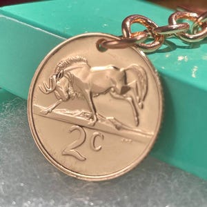 Collar o llavero con moneda de ñu: Monedas sudafricanas de 2 centavos, 1965-1989, ñu salvaje