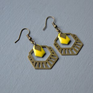 Könnte beinhalten: Ein Paar goldene Ohrringe mit geometrischem Design und einem gelben, rautenförmigen Akzent.