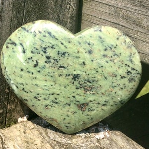 May include: A green heart-shaped stone with black and brown speckles.