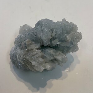 Pu&ograve; includere: Un ammasso di cristalli di celestite blu chiaro con una texture ruvida e naturale.