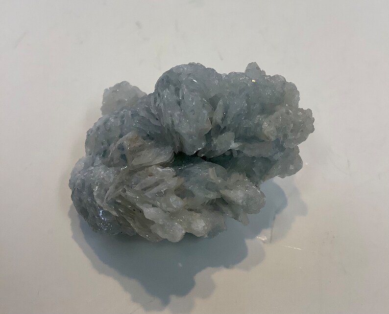Pu&ograve; includere: Un ammasso di cristalli di celestite blu chiaro con una texture ruvida e naturale.
