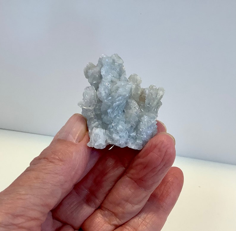 Pu&ograve; includere: Un gruppo di cristalli di celestite blu chiaro con una superficie ruvida e testurizzata.