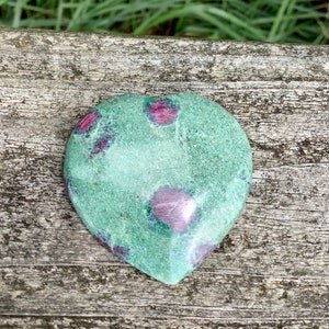 May include: Green and pink heart-shaped stone with a polished surface. The stone has a natural, organic pattern of pink and green.