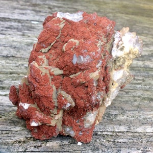 May include: A cluster of clear quartz crystals embedded in a reddish-brown matrix. The crystals are sharp and well-defined, and the matrix is rough and textured.