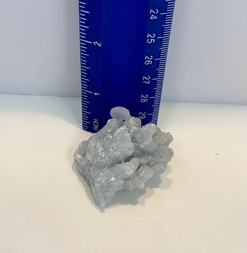 Pu&ograve; includere: Un ammasso di cristalli di celestite blu chiaro, che misura circa 5 cm di diametro, con un righello per la scala.