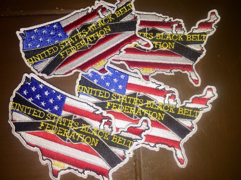 May include: Three embroidered patches in the shape of the United States of America. Each patch features a black and white striped ribbon across the American flag with the text "United States Black Belt Federation" in yellow.