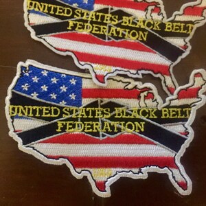 May include: Two embroidered patches in the shape of the United States of America. The patches are red, white, and blue with a black ribbon across the middle. The ribbon has the text "United States Black Belt Federation" in yellow lettering.