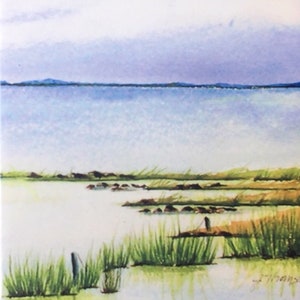 May include: A watercolour painting depicting a seascape with a distant shoreline, a pale blue sky, and green marsh grasses in the foreground.