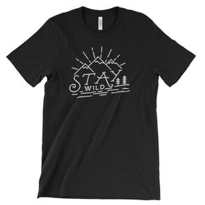 May include: Black t-shirt with a white graphic design of mountains and trees. The text "Stay Wild" is written below the mountains.
