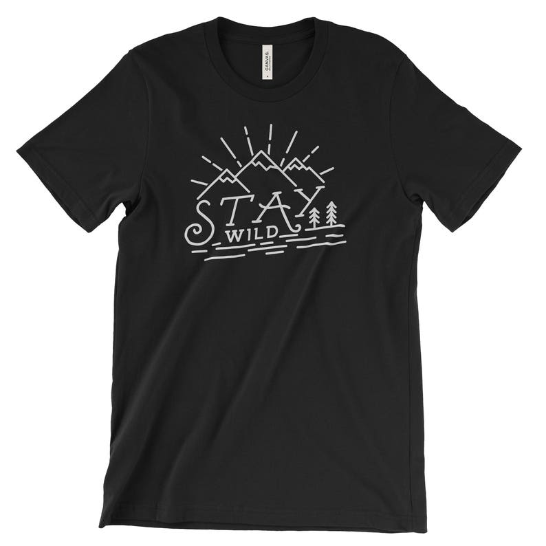 May include: Black t-shirt with a white graphic design of mountains and trees. The text "Stay Wild" is written below the mountains.