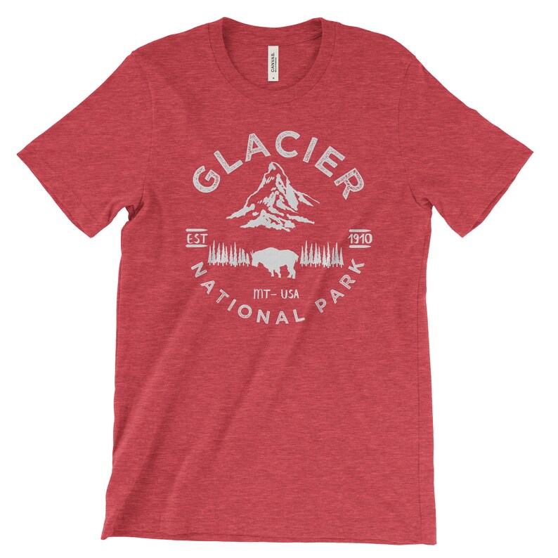 Peut inclure: T-shirt rouge en heather avec un motif blanc du parc national de Glacier, Montana, &Eacute;tats-Unis. Le motif comprend le nom du parc, une cha&icirc;ne de montagnes, un bison et les ann&eacute;es "EST 1910".
