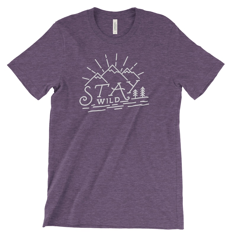 May include: Purple heather t-shirt with a white graphic of mountains and trees with the text "Stay Wild".