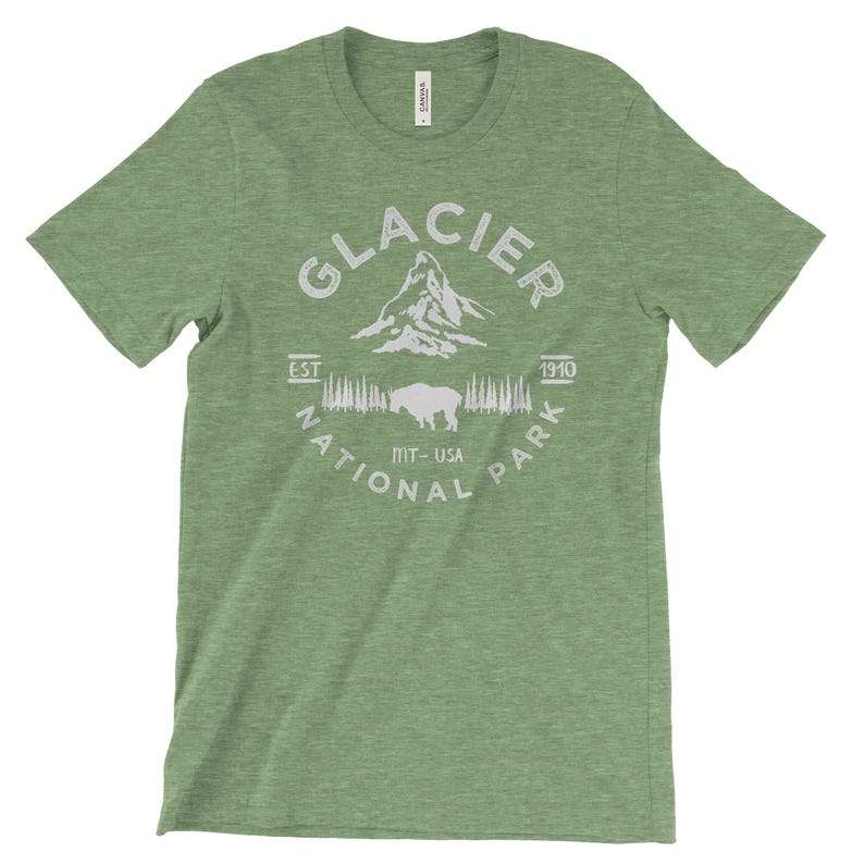 Peut inclure: T-shirt vert avec un motif blanc du parc national de Glacier, Montana, &Eacute;tats-Unis. Le motif comprend une montagne, des arbres, un bison et le texte "Glacier National Park Est. 1910".