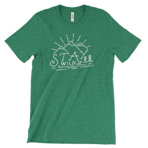 May include: A green t-shirt with a white graphic design of mountains and trees. The text "Stay Wild" is written below the mountains.
