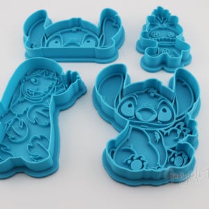 May include: A collection of four blue plastic cookie cutters in various shapes, featuring characters from a popular animated film. The cutters include the character Stitch in different poses, and another character. Ideal for baking themed treats.
