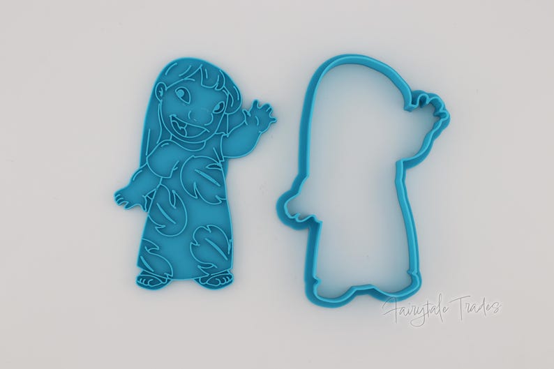 May include: Two blue plastic cookie cutters in the shape of a cartoon character. One cutter is a solid form, and the other is an outline. The character is waving with a smiling expression.