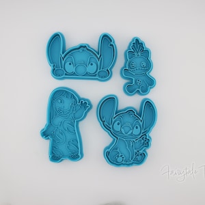 May include: Four teal-colored cookie cutters featuring characters from the animated film Lilo & Stitch. The cutters depict Stitch in various poses and a character named Angel. The cutters are made of plastic and are on a white background.