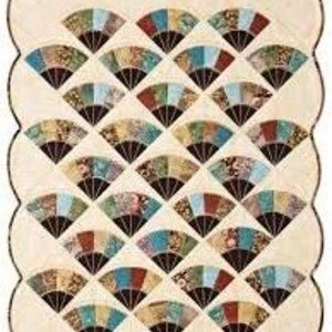 May include: A quilted wall hanging featuring a repeating fan pattern in shades of blue, red, green, and gold. The fans are arranged in a grid on a cream-colored background, with a scalloped border.