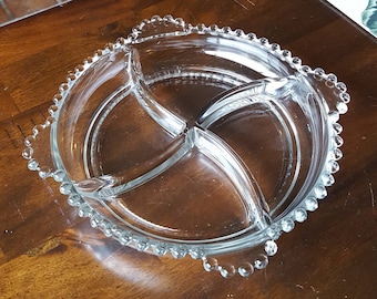 Könnte beinhalten: Eine klare Glasservierplatte mit vier Abschnitten. Die Platte hat einen perlenbesetzten Rand.