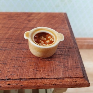 May include: A set of three ceramic mugs with a speckled, matte finish. The mugs are in shades of cream, light gray, and dark gray. Each mug has a simple, minimalist design and a rounded handle.