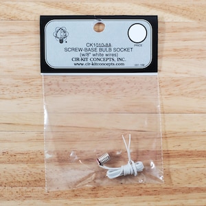 May include: A screw-base bulb socket with 8-inch white wires, packaged in a clear plastic bag. The product label includes the text "CK1010-8A SCREW-BASE BULB SOCKET (w/8" white wires) CIR-KIT CONCEPTS, INC."