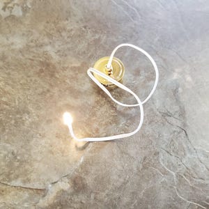 Bombilla miniatura a pilas en guirnalda de luces cálidas para casas de muñecas.