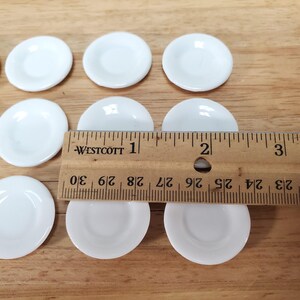 Pu&ograve; includere: Una collezione di piccoli piatti rotondi in ceramica bianca disposti in file. Un righello in legno Westcott &egrave; posizionato sopra i piatti, mostrando che ogni singolo piatto ha un diametro di circa 2,54 cm.