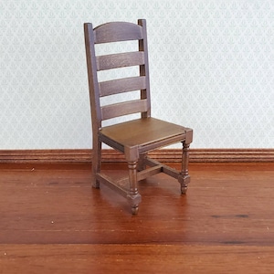 May include: A miniature wooden chair with a ladder back and a brown seat. The chair has four legs and is designed with a classic style. The chair is a dollhouse or miniature furniture item.