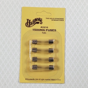 May include: A yellow card with four 1500MA fuses in a clear plastic package. The card has the text "Houseworks" and "THE GOLD STANDARD IN MINIATURES". The package contains four fuses.