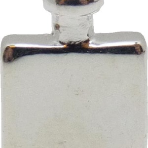 May include: A small, silver-colored metal bottle stopper. The stopper has a rectangular base with a rounded top and a circular knob on top. The metal has a shiny, reflective surface.